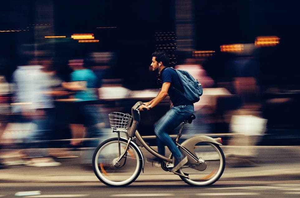 Ciclista urbano pedaleando por la ciudad con el fondo en movimiento